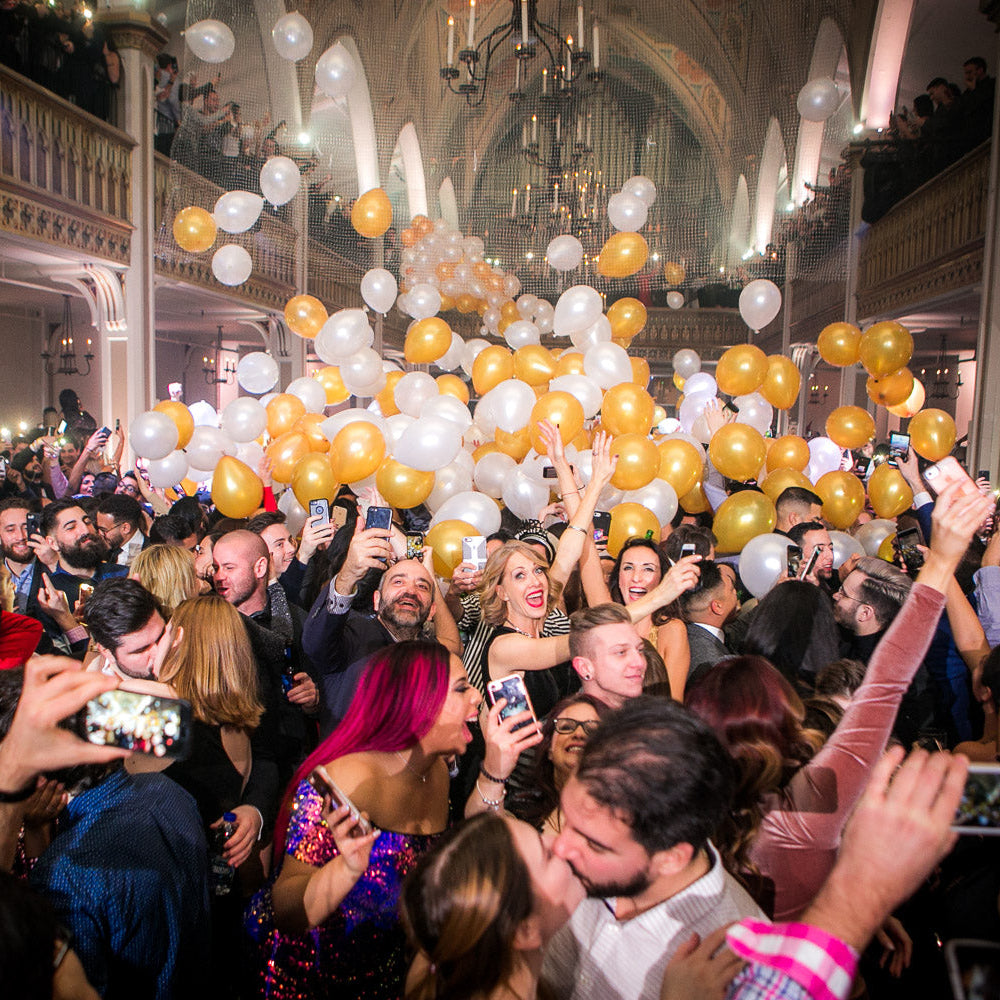 Crowd celebrating with a gold and white balloon drop at midnight during the Final Fantasy New Year’s Eve party at Salon Richmond in Montreal.